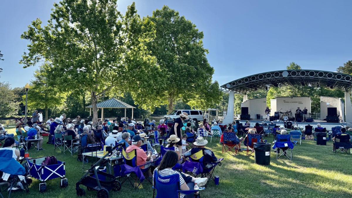 A large crowd of guests in lawn chairs and on blankets surround the Heritage Park stage for Some Enchanted Evening with the Northshore Community Orchestra.