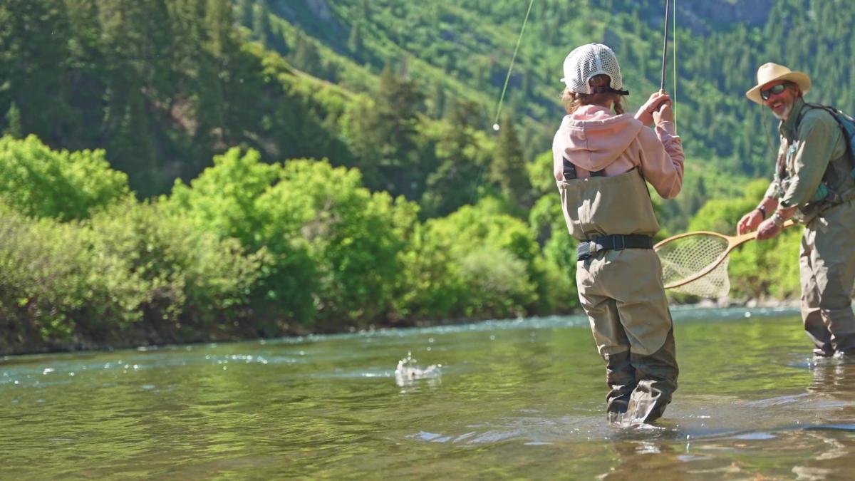Little girl catching fish on a river
