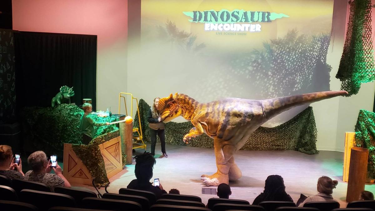An audience takes in a dinosaur during the dinosaur encounter at Exploration Place