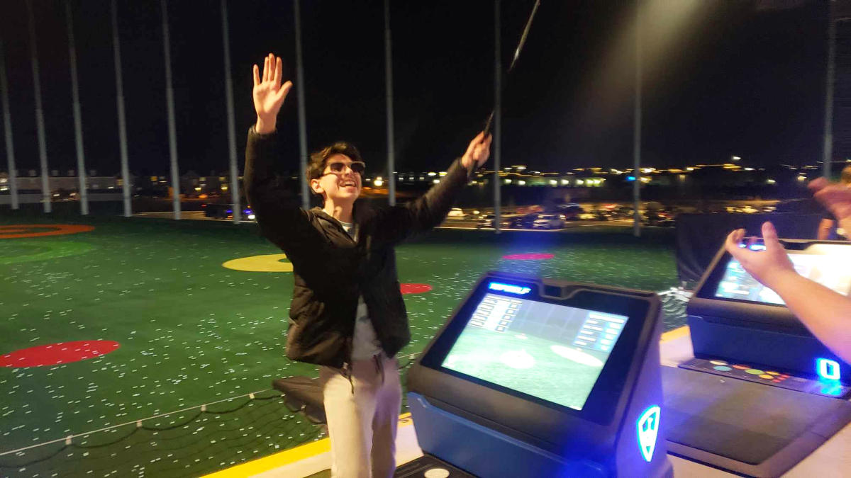 A teen boy celebrates after hitting a ball at Topgolf Wichita.