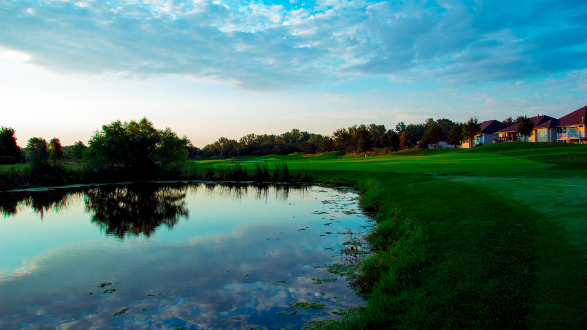 The sun sets over a pond at Auburn Hills Golf Course