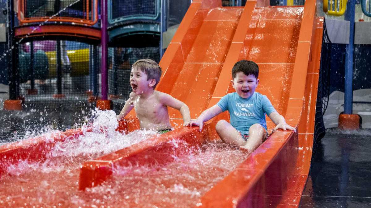 Two boys smile as they go down the slide at Blast Off Bay Water Park