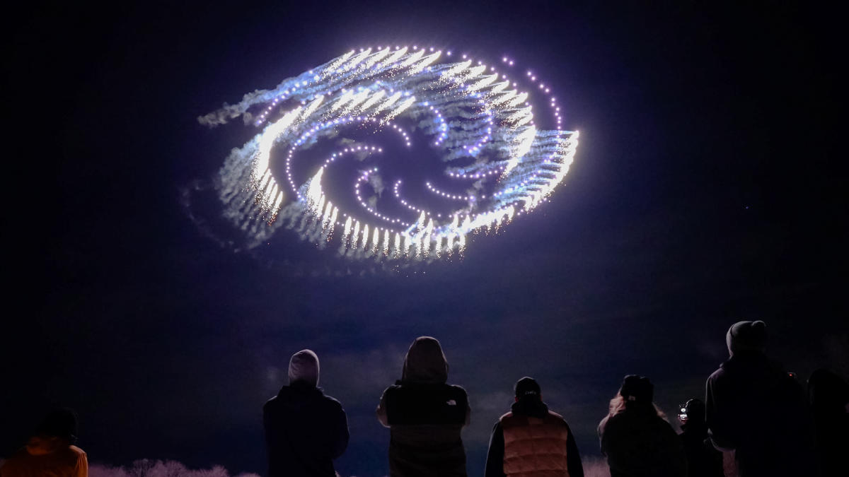 Flames shoot from drones flying high above the sky as onlookers marvel.