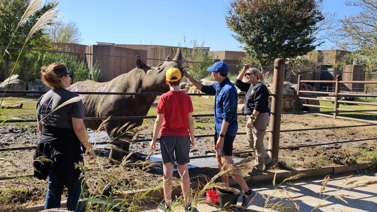 Three people enjoy an encounter with a rhino at the Sedgwick County Zoo