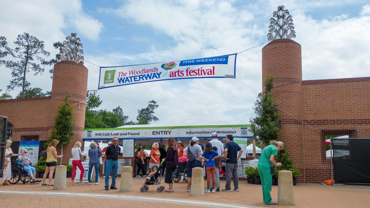 People admiring artwork at The Woodlands Waterway Arts Festival in The Woodlands, Texas