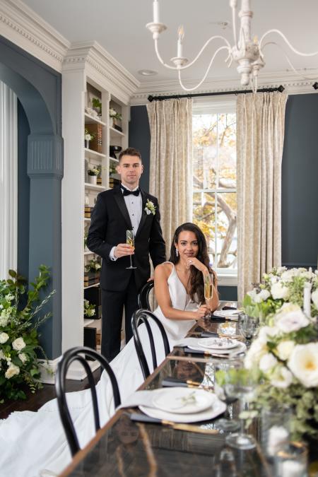 A bride and groom pose for a photo in a luxe dining room