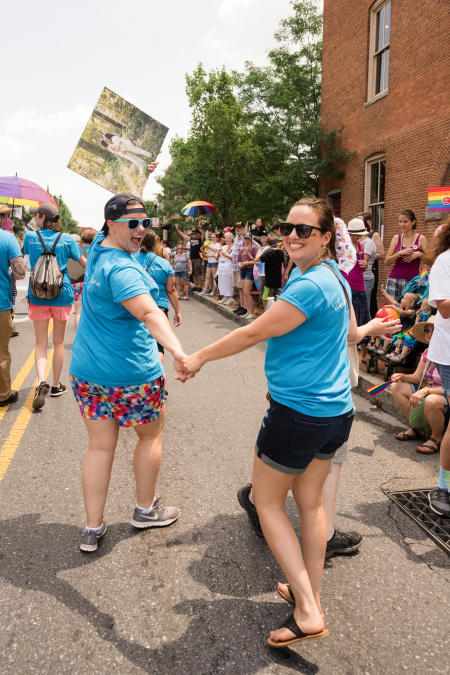 Two women holds hands and walk in the Annapolis Pride Parade