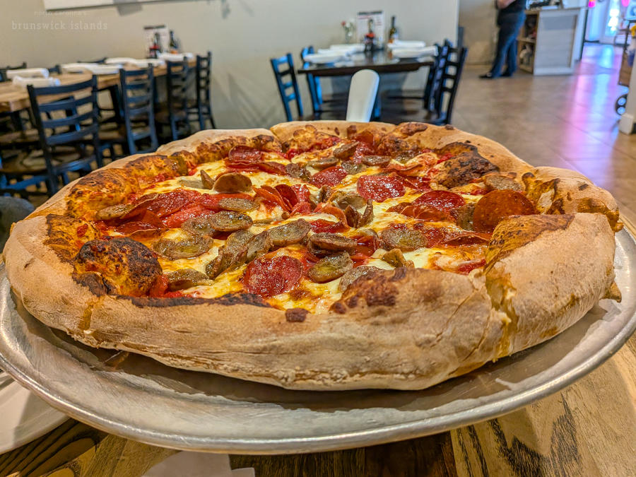 a thick crusted pizza topped with sausage and pepperoni from Maria's Pizzeria in Ocean Isle Beach