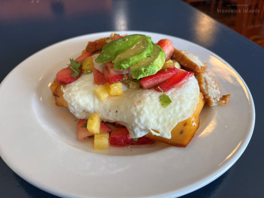 a plate of fruit, avocado, fried chicken, and an egg