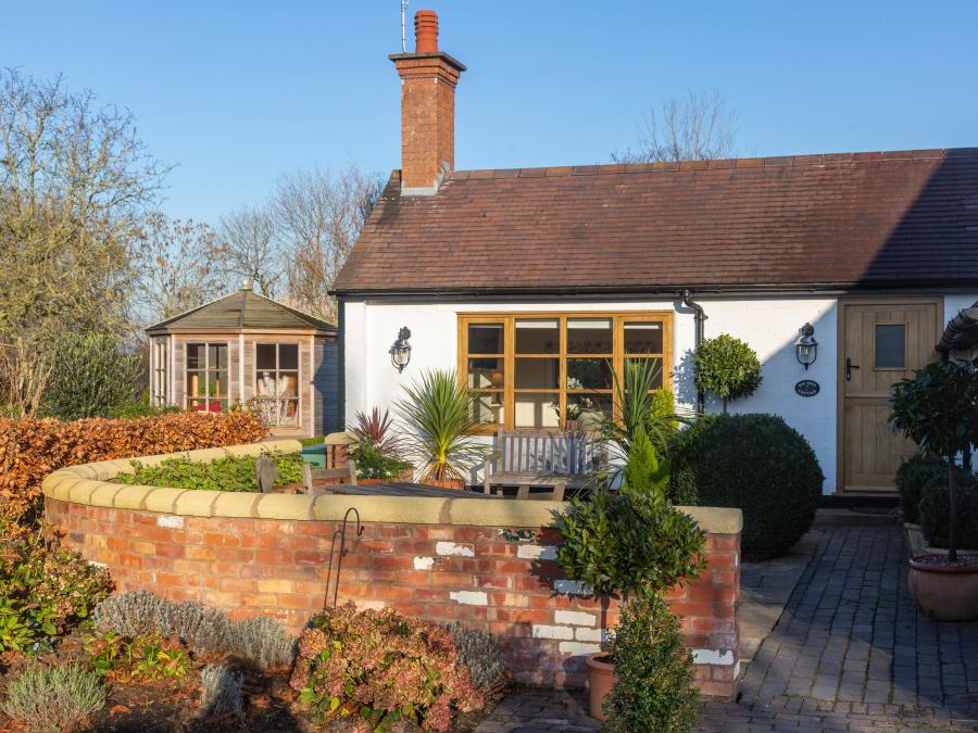 Bay Tree Cottage, a white chalet cottage surrounded by a walled garden