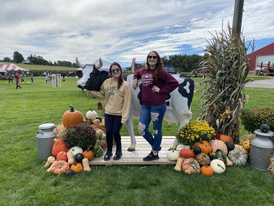 Two friends taking a photo op with a fake cow at Fun on the Farm
