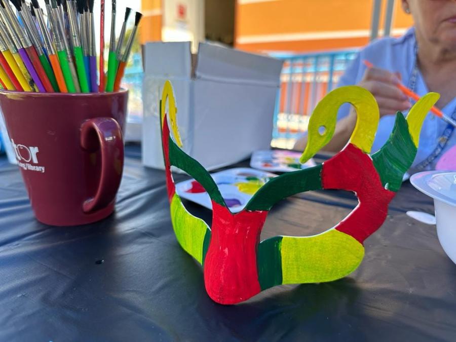 A hand-painted mask sitting on top of an arts and crafts table
