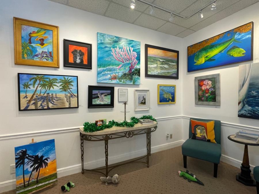 A corner of an art gallery with many colorful paintings of beach scenes