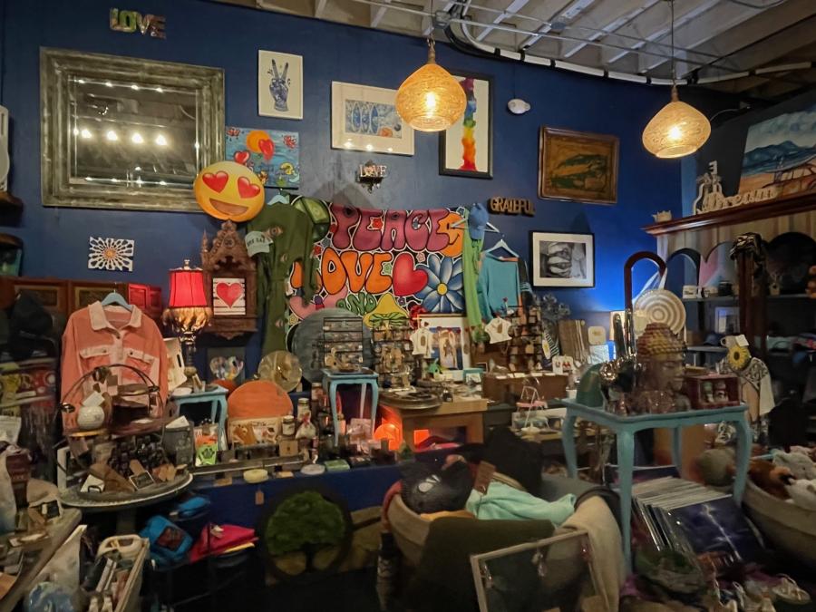 An area with many handmade gifts and art displayed on several small tables and hanging on a wall painted blue.