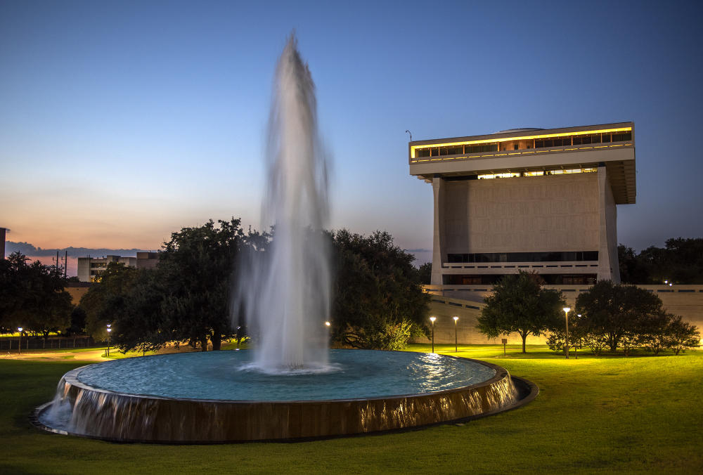 Fountain outside of an illuminated LBJ Library at dusk.
