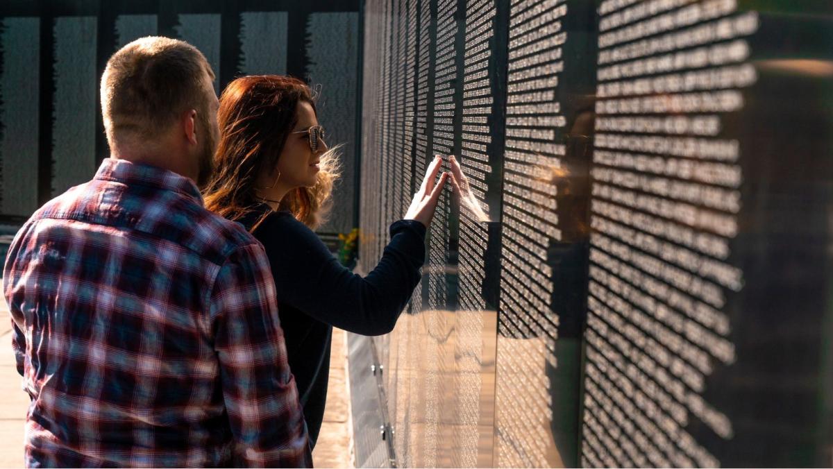 a woman touching names on the veterans memorial wall