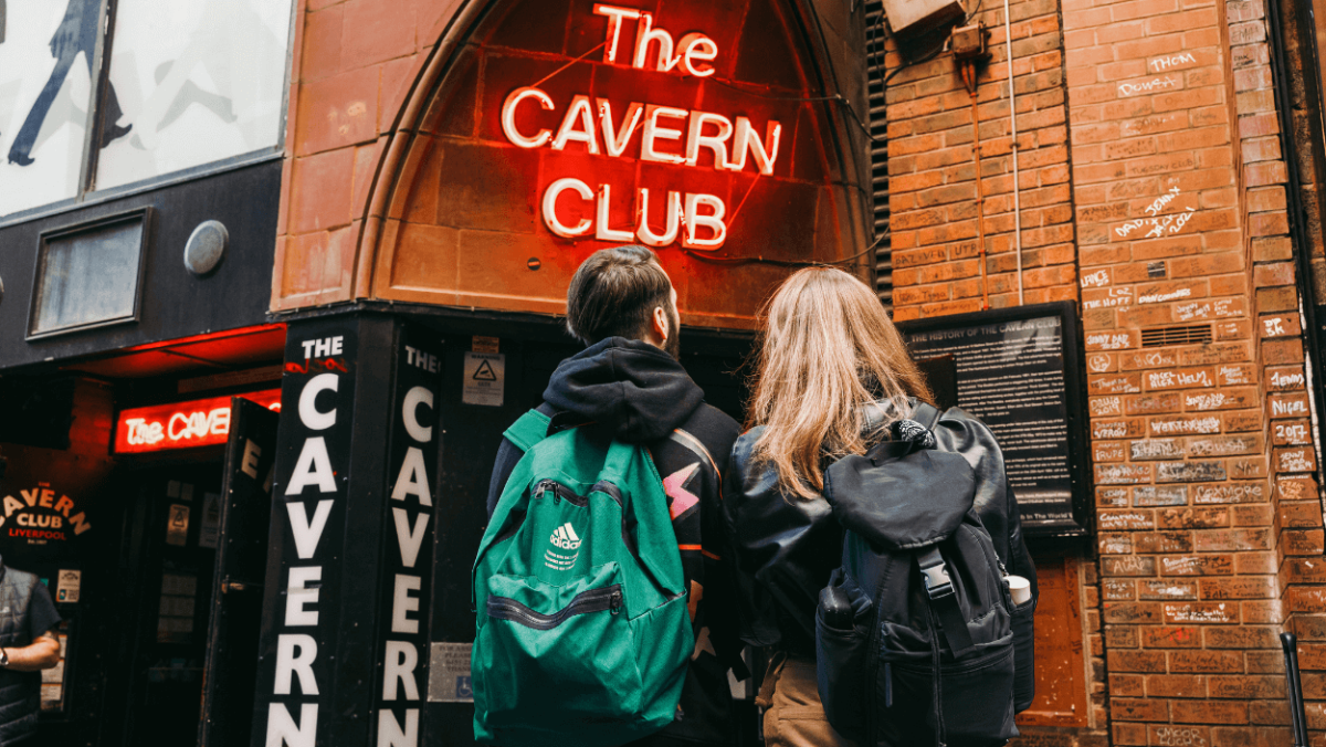 People standing outside the Cavern Club with the sign illuminated