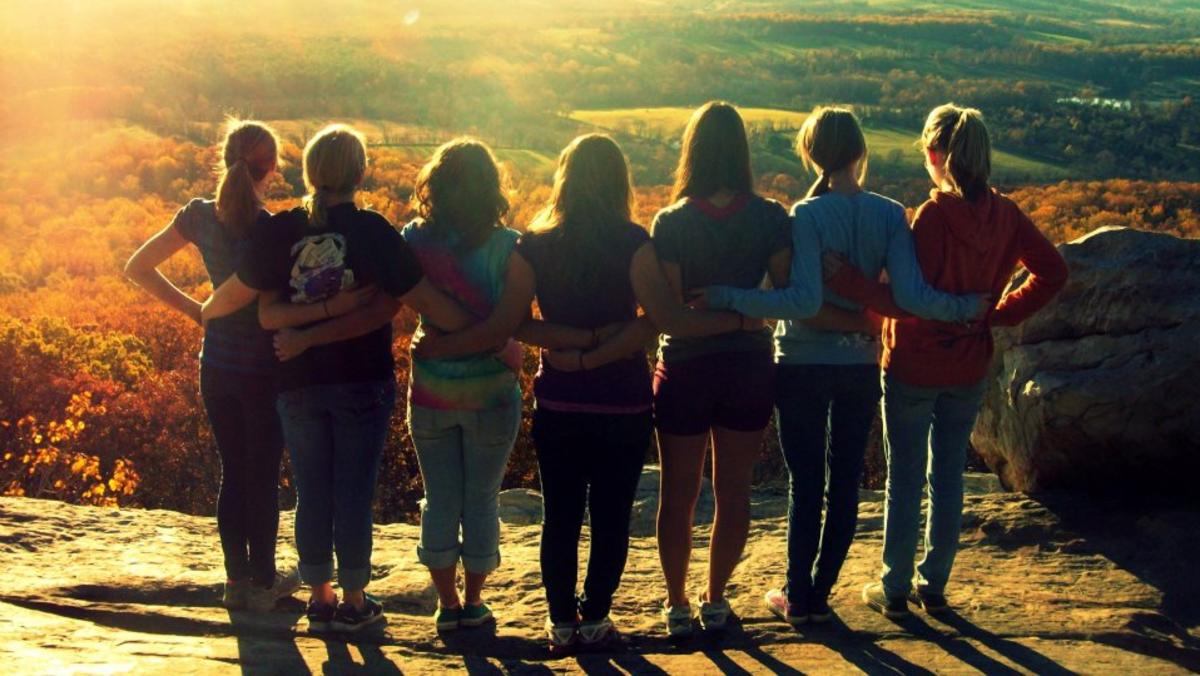 group of women standing together on top of a mountain