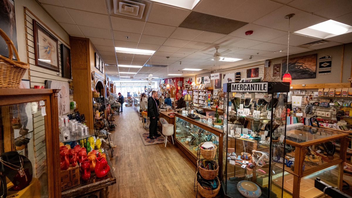 A cozy, bustling mercantile store with various goods on wooden shelves and display cases. Customers browse, creating a warm, nostalgic ambiance.