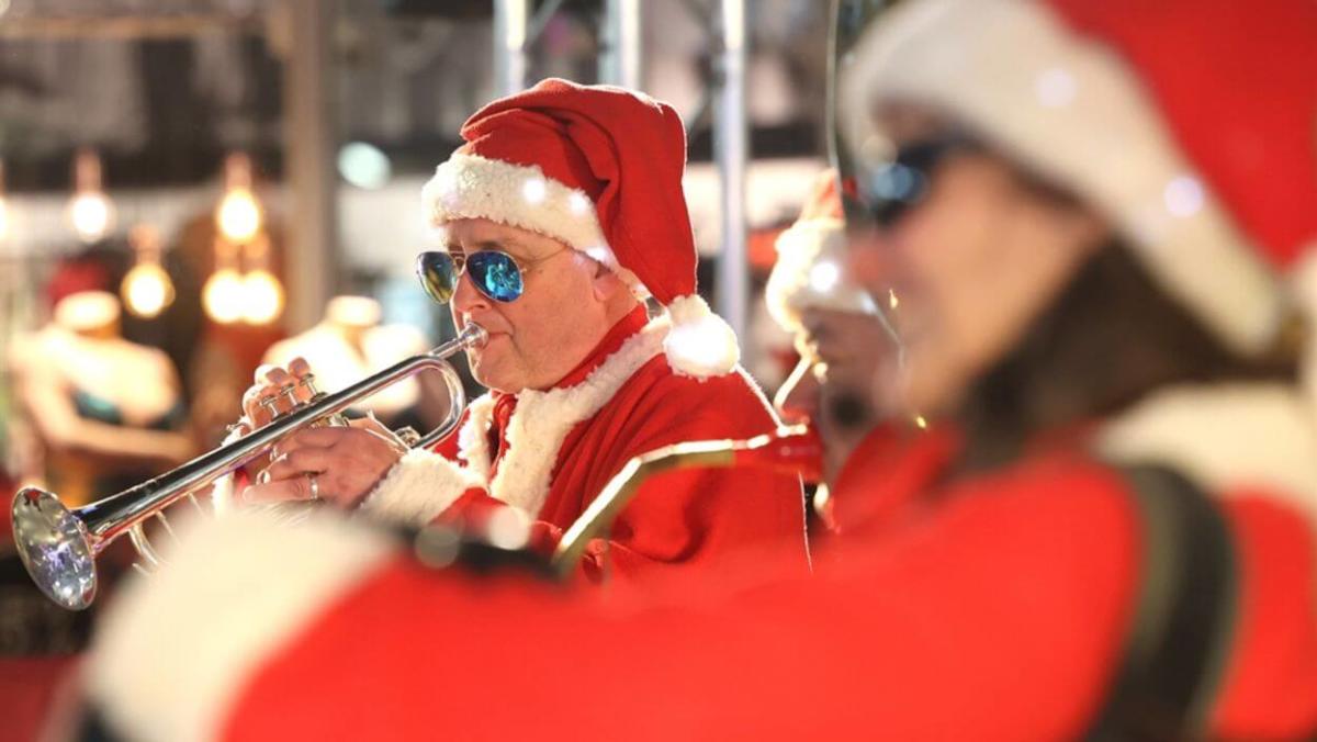Man dressed as santa plays a trumpet