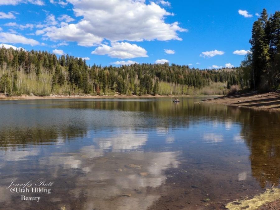 white clouds and blue sky reflect in glassy water of Payson Lakes, surrounded by tall aspen trees