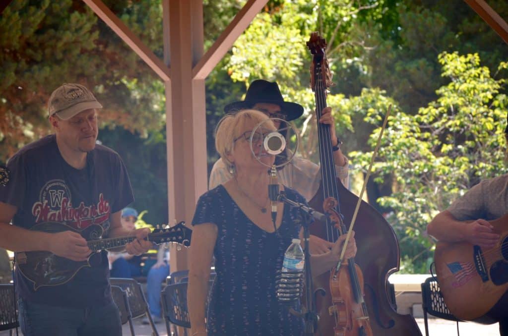 A bluegrass band plays their instruments under a wood pergola at the Centennial Village Museum during Potato Day