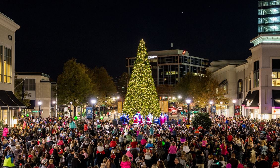 Large crowd of people surround a tall, lit Christmas tree at the North Hills Tree Lighting Celebration