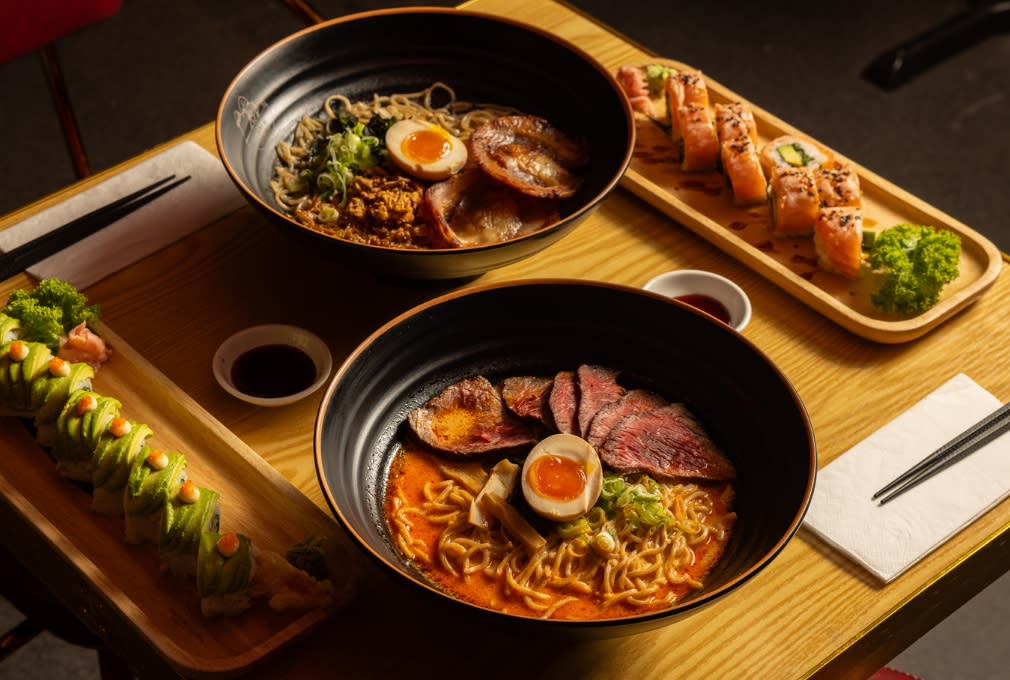 Big bowls of ramen dishes with egg, noodles and beef along side sides of sushi at Maki & Ramen