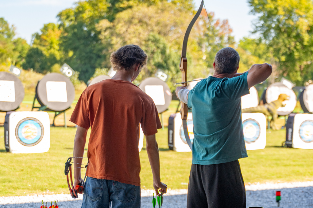 Two visitors to the archery range, standing and getting ready to shoot their arrows.