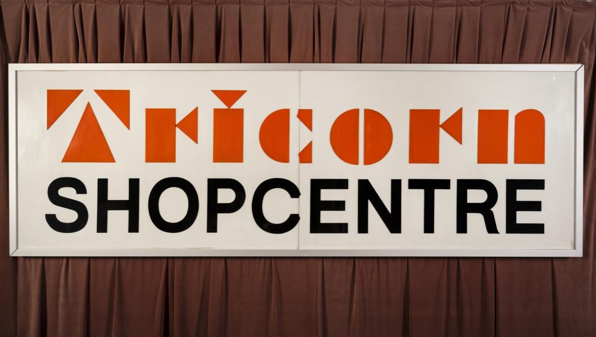 An original Tricorn sign with a dark curtain behind it.