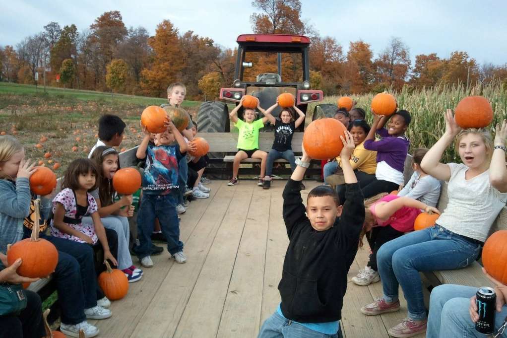 ϾKids holding pumpkins riding a tractor trailer at Joe Huber Pumpkins}}