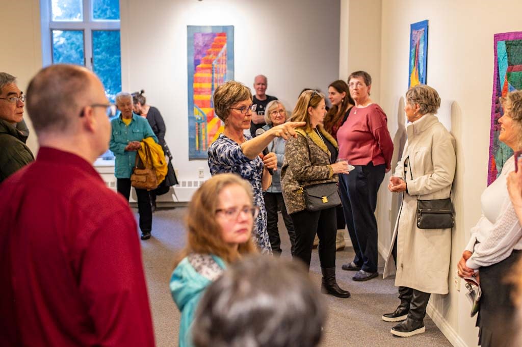 an artist addresses a group of people in an art gallery