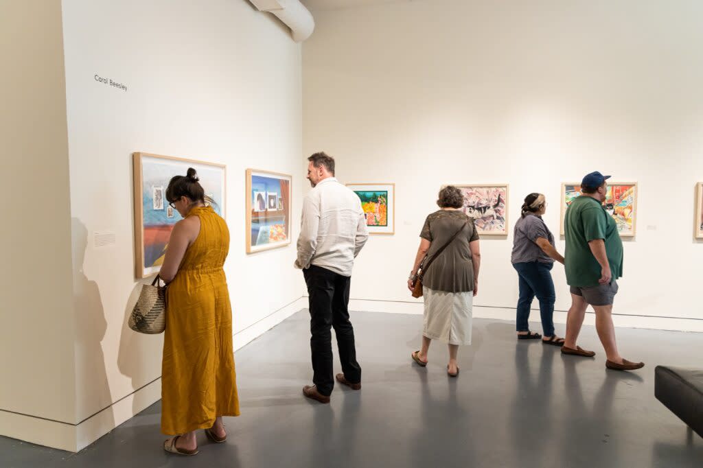 A group of people viewing art hung on a wall during 2nd Friday Norman Art Walk