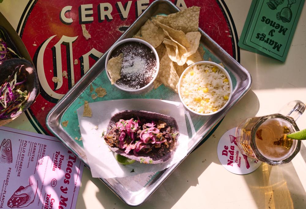 Taco, chips and dip and beer on a colorful table.