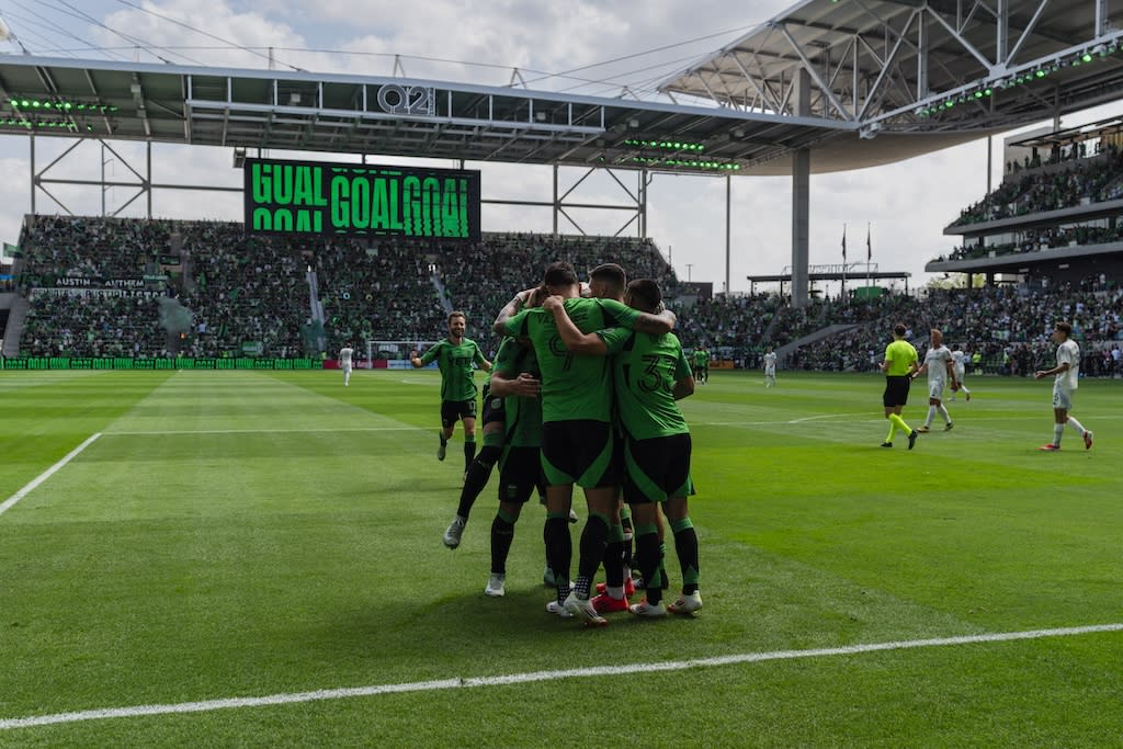 Image of some Austin FC players huddling on the field at Q2 Stadium during a game.