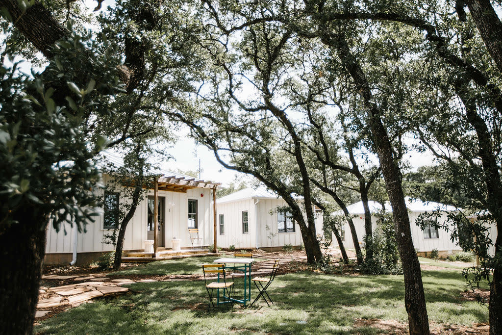 Image of white cottages and nestled among green trees at The Wayback.