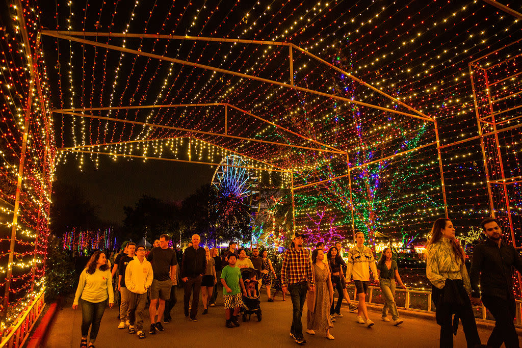 Image of a large group of people walking under the tunnel of lights.