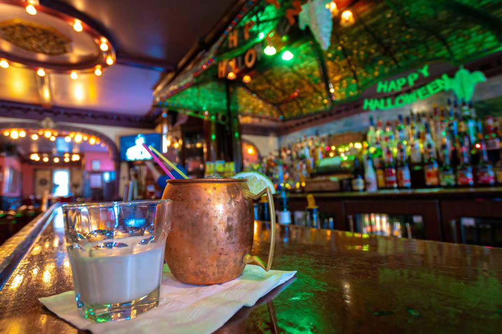 two drinks on the bar with bottles in the background