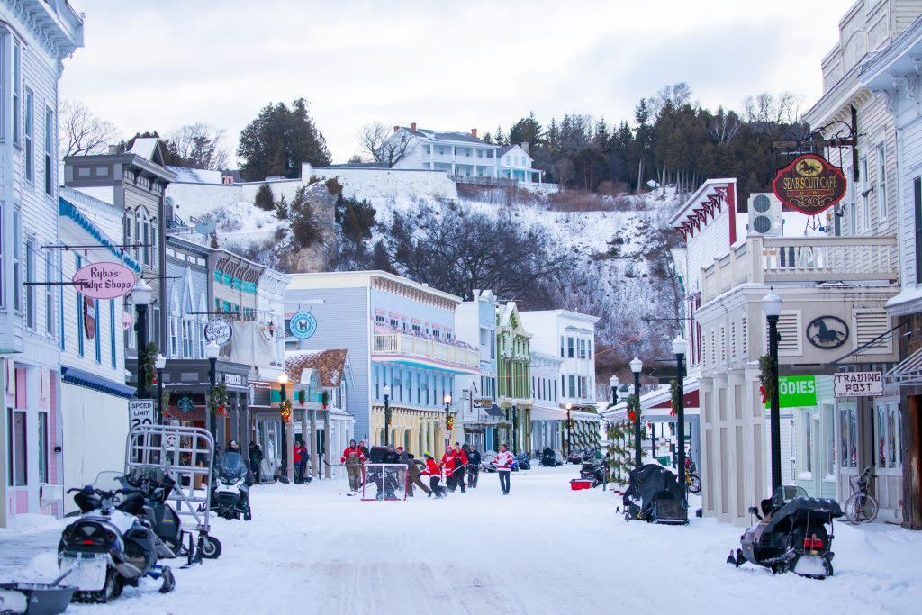 Snowmobiles line Mackinac Island's downtown as a hockey game is played in the middle of the street