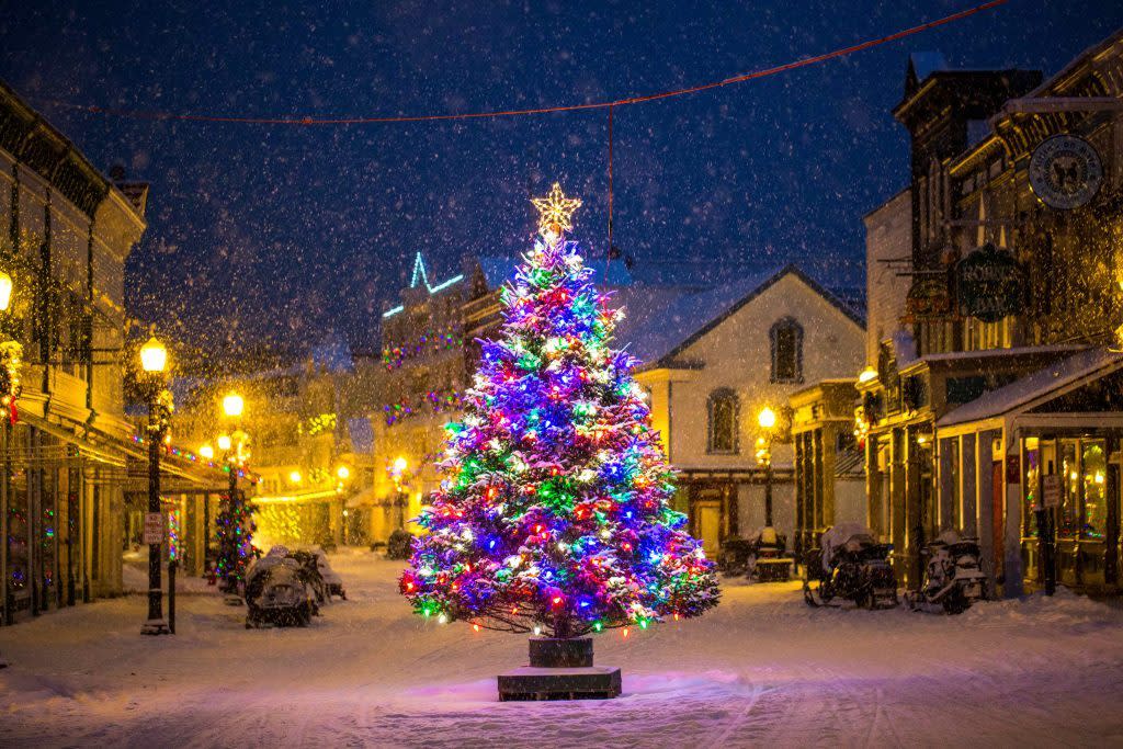 A Christmas tree with multicolored lights sparkles in the middle of Mackinac Island’s snowy Main Street on a winter night