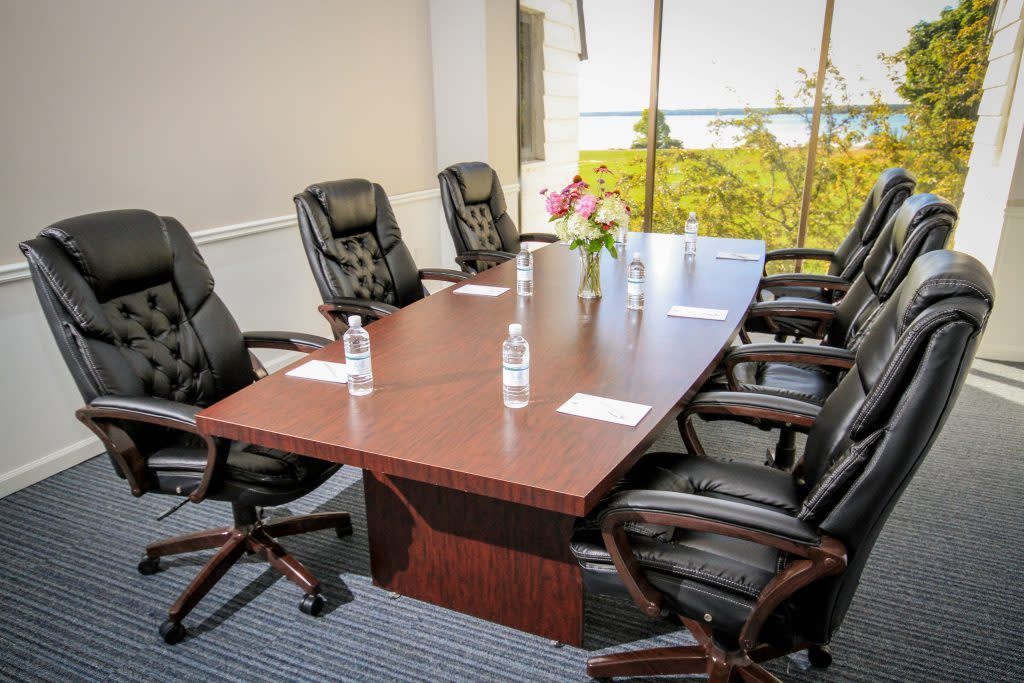 Six chairs sit around a conference table at Mission Point Resort overlooking the water outside
