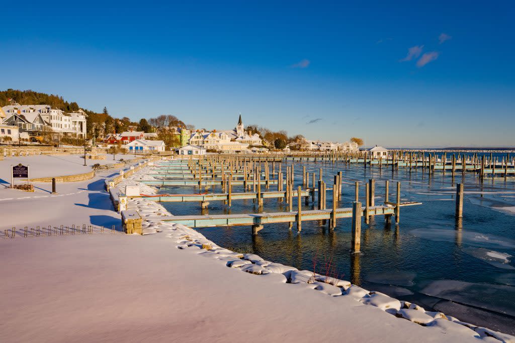 Snow covers the shoreline by the docks of the Mackinac Island marina on a sunny winter day