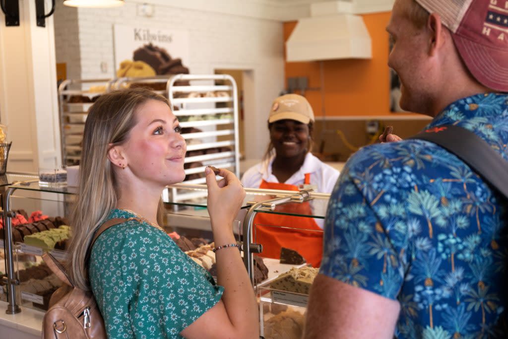 A young couple samples pieces of world-famous Mackinac Island fudge as a fudgemaker watches from behind the counter and smiles