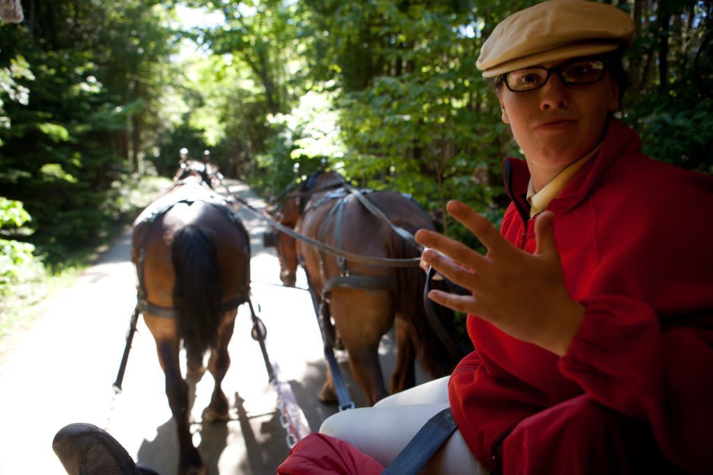A Mackinac Island Carriage Tours guide narrates a tour being led by two horses