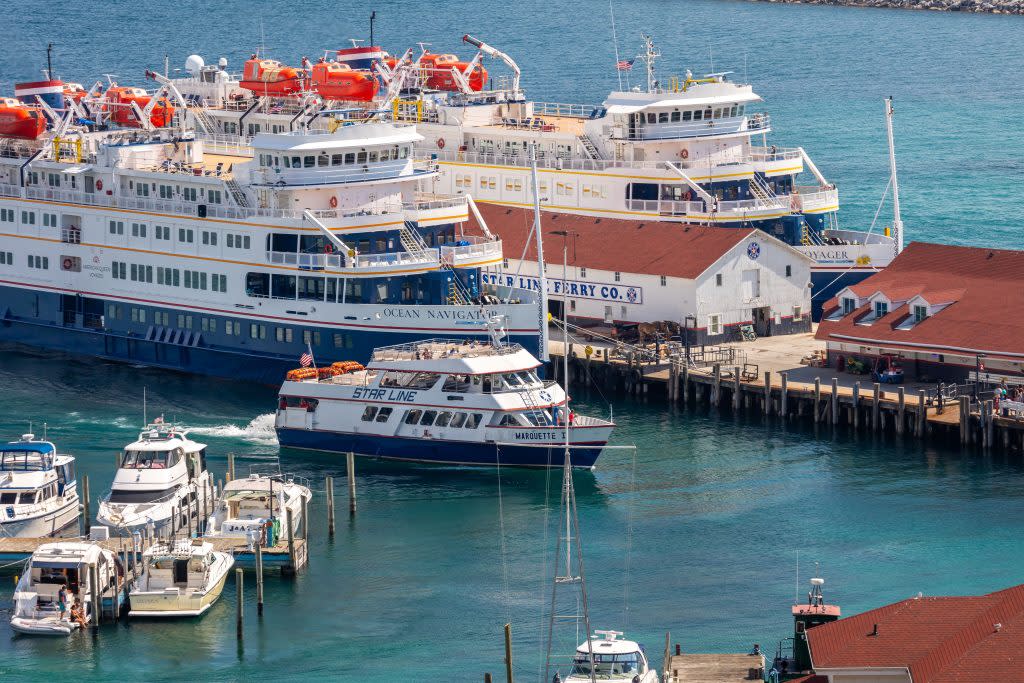 A Great Lakes cruise ship towers above an incoming Mackinac Island ferry boat at the dock on Mackinac Island