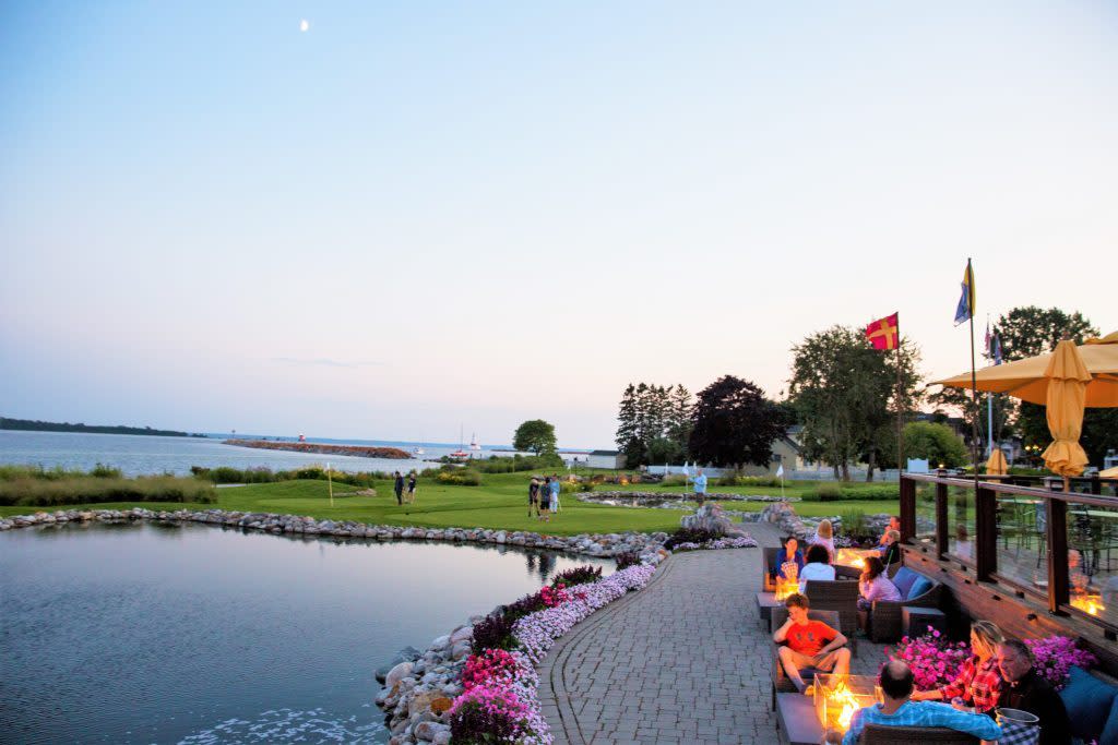 A fire lights up a table at Mission Point Resort's Bistro on the Greens as people play putt putt golf at sunset on Mackinac Island