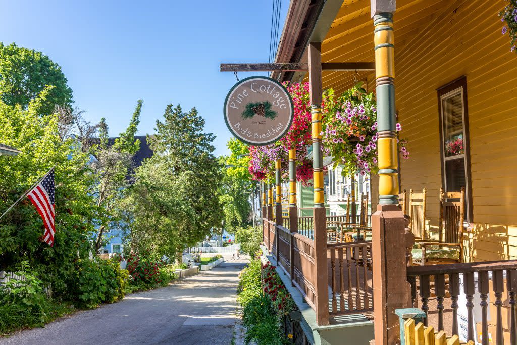 A Pine Cottage Bed & Breakfast sign hangs on the wraparound porch at the B&B on Mackinac Island’s Bogan Lane. 