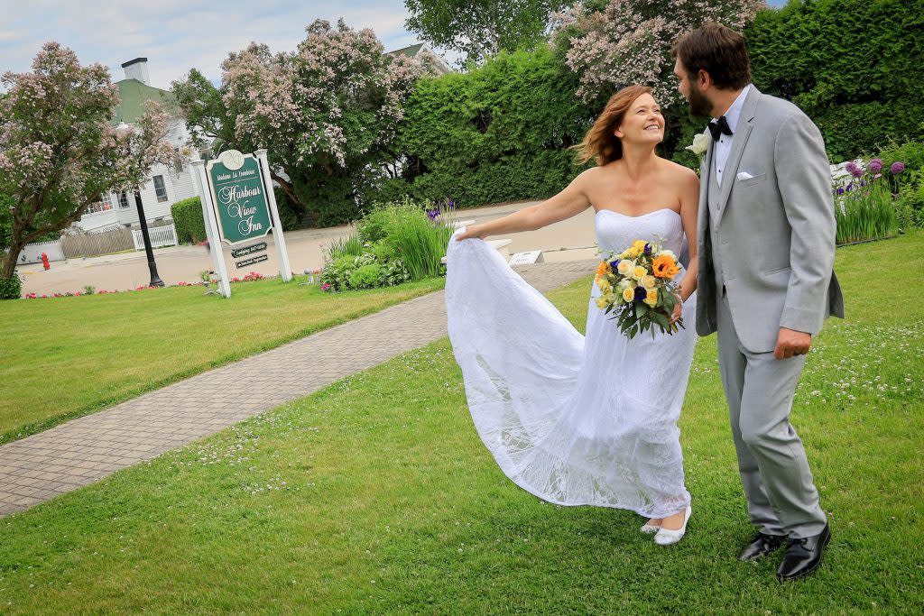A bride and groom pose for pictures on the lawn of a popular Mackinac Island wedding venue, Harbour View Inn.