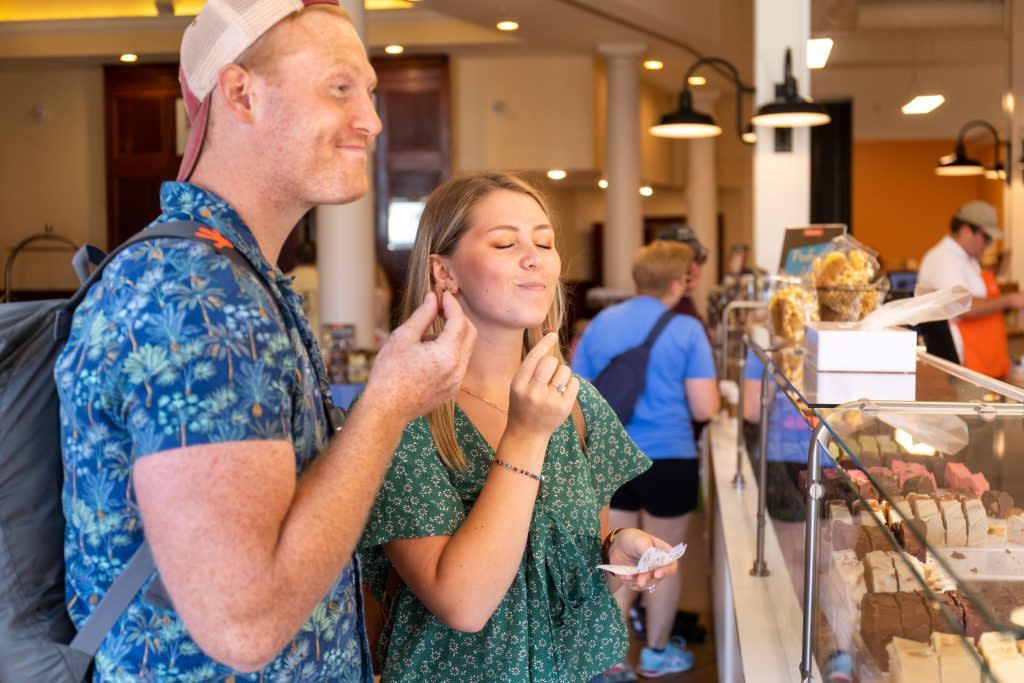 A young man and woman react to the taste of world-famous Mackinac Island fudge while sampling flavors inside a shop