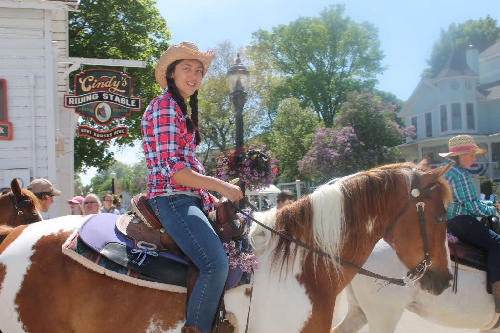A young woman saddles up for a horseback ride at Cindy’s Riding Stable on Mackinac Island